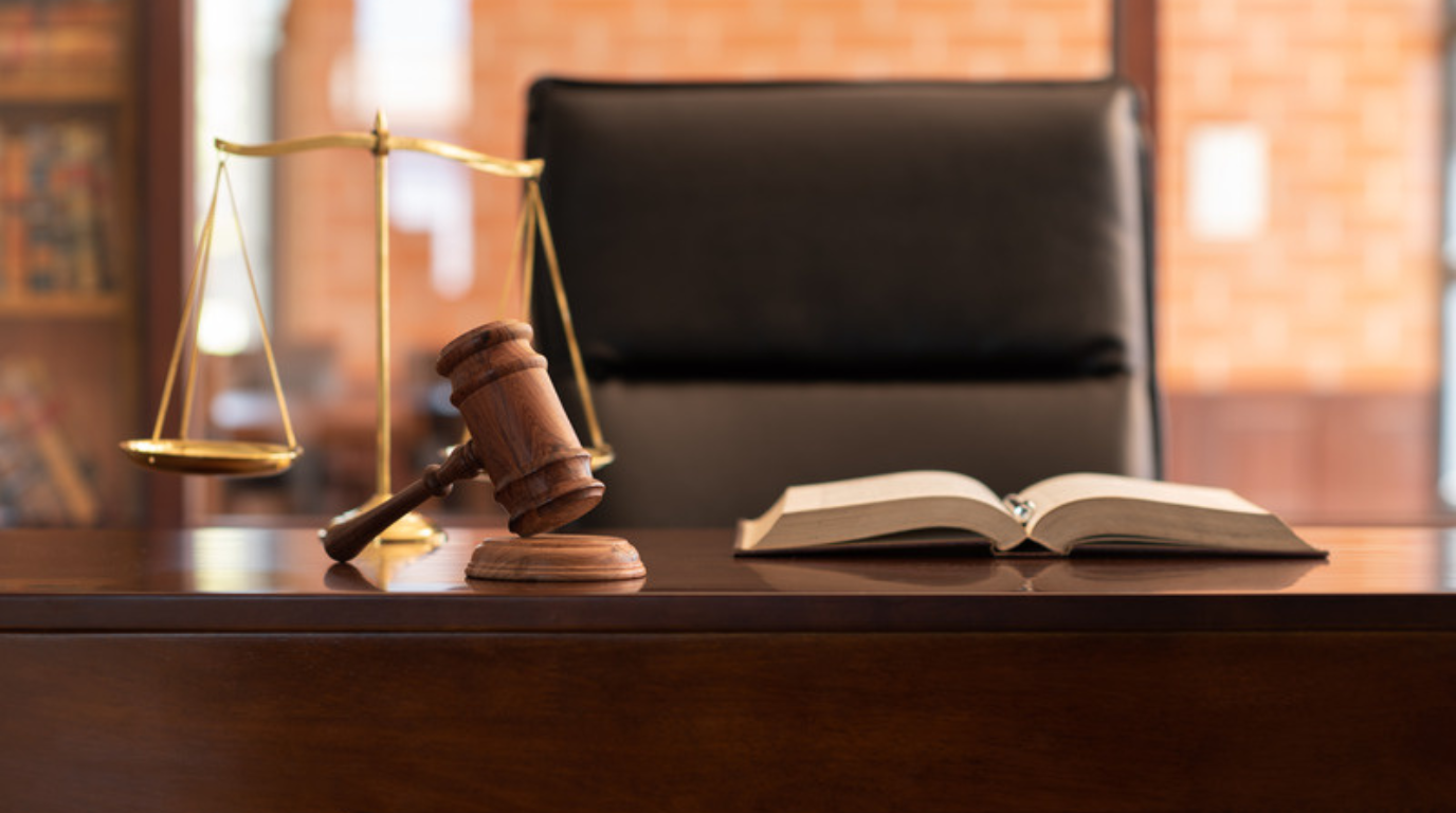 A judge's desk with a wooden gavel, an open book, and a brass balance scale in a Utah courtroom—ideal for a Personal Injury Attorney in Kamas seeking justice.