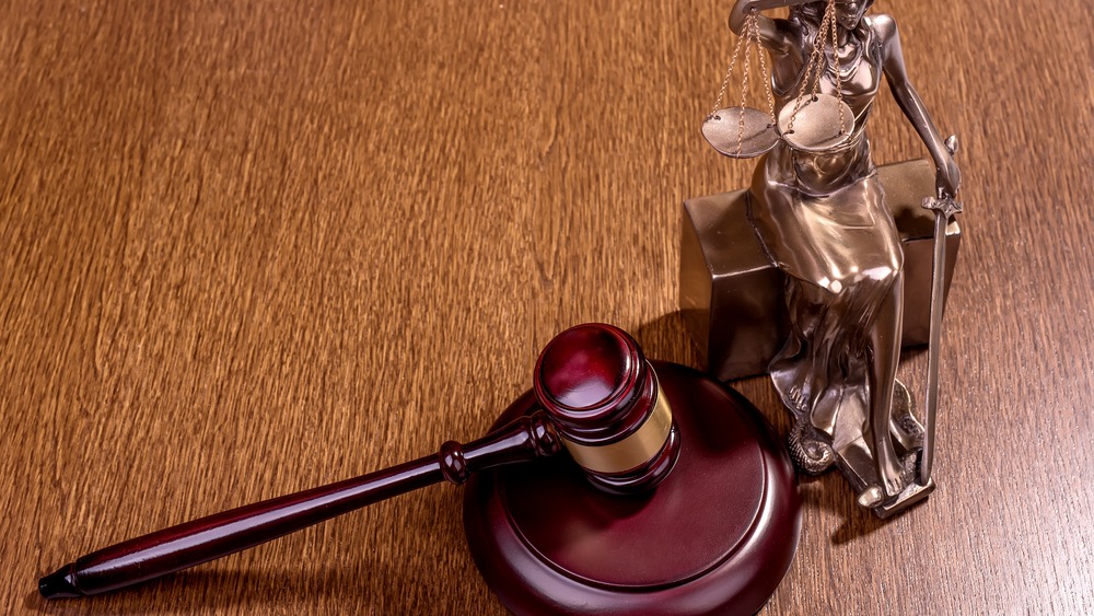 A judge's gavel and a bronze statue of Lady Justice holding scales rest on a wooden surface, symbolizing the commitment of a Park City personal injury lawyer to justice in Utah.
